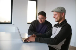 Twee mannen concentreren zich op een laptop in een lichte, moderne kantoorruimte