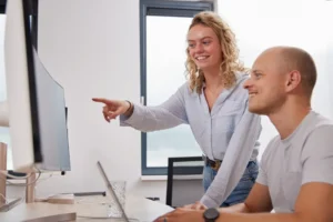 Een vrouw en man werken samen in een lichte kantooromgeving met natuurlijk licht.