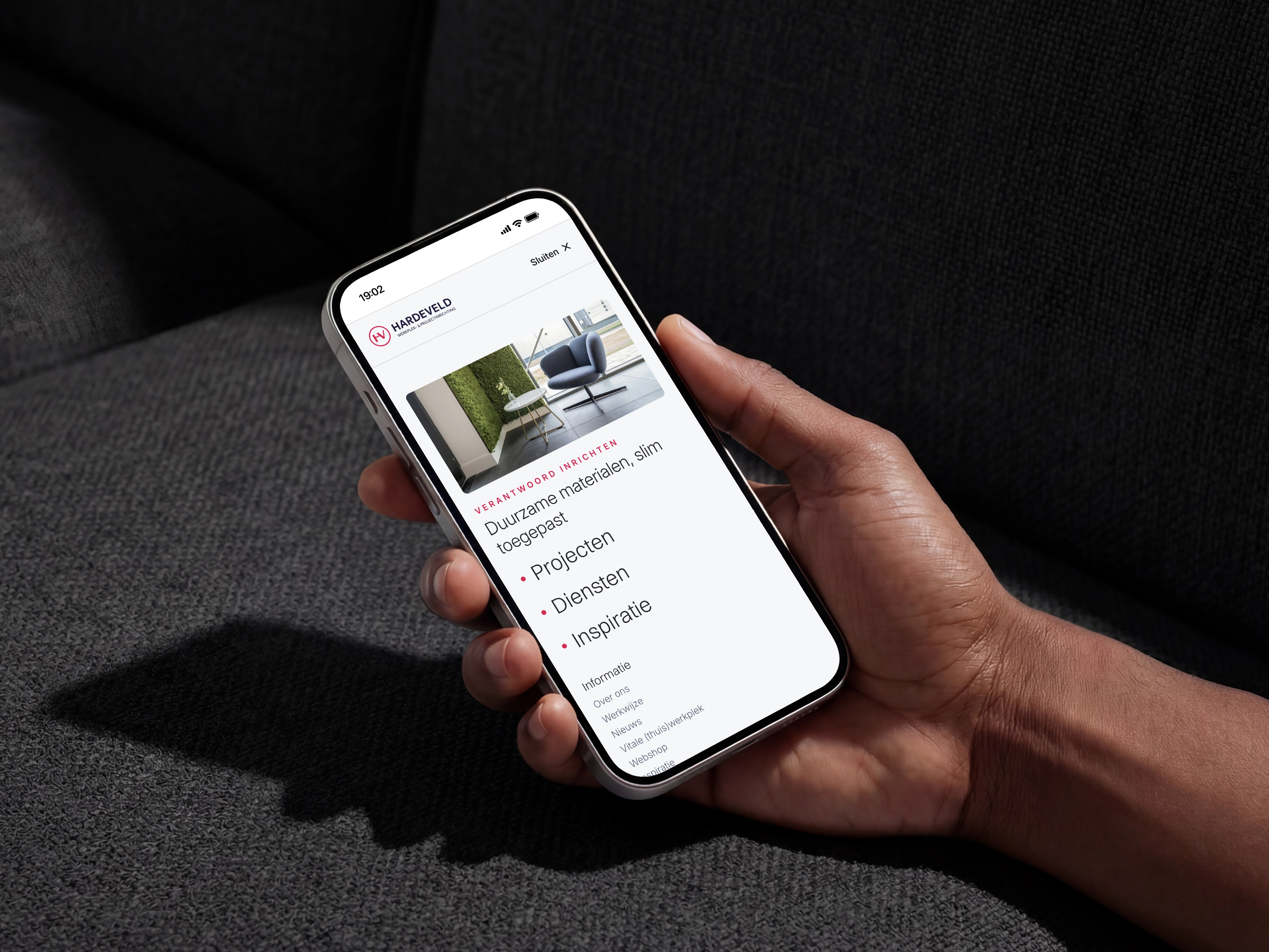 Hand die een smartphone vasthoudt met een website over duurzame materialen genaamd Hardeveld zichtbaar.