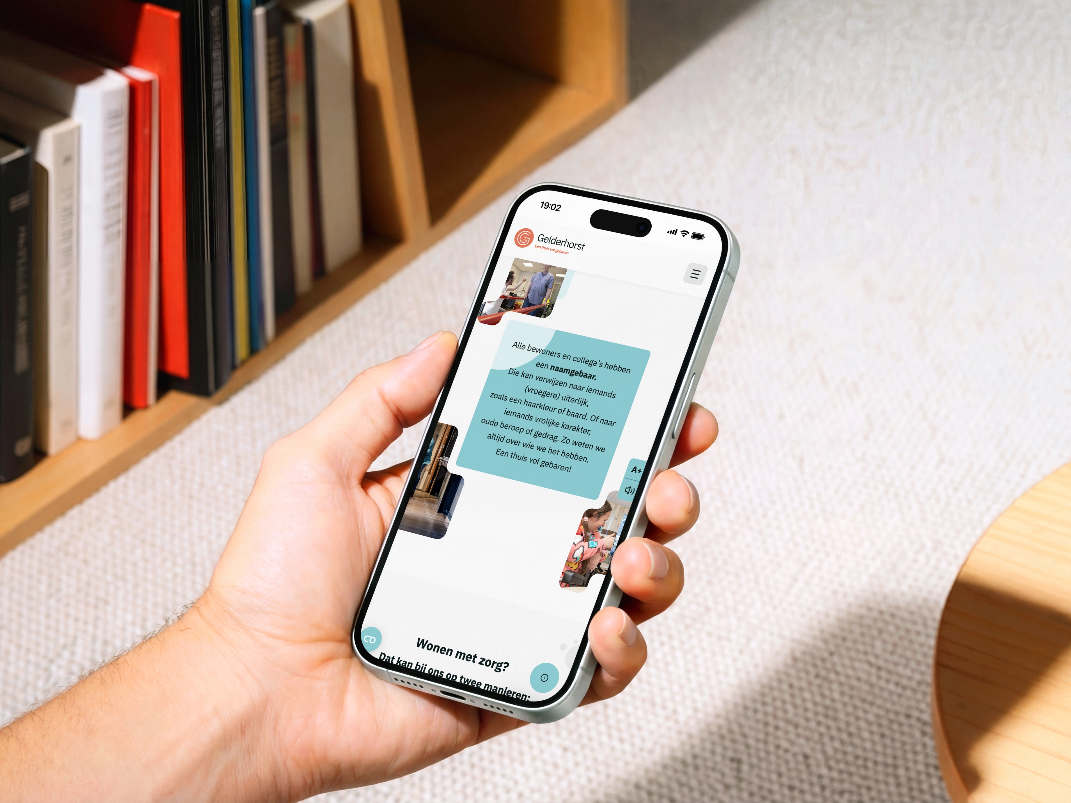 Hand die een smartphone vasthoudt met chatberichten over zorg, boekenplank en houten tafel op de achtergrond.