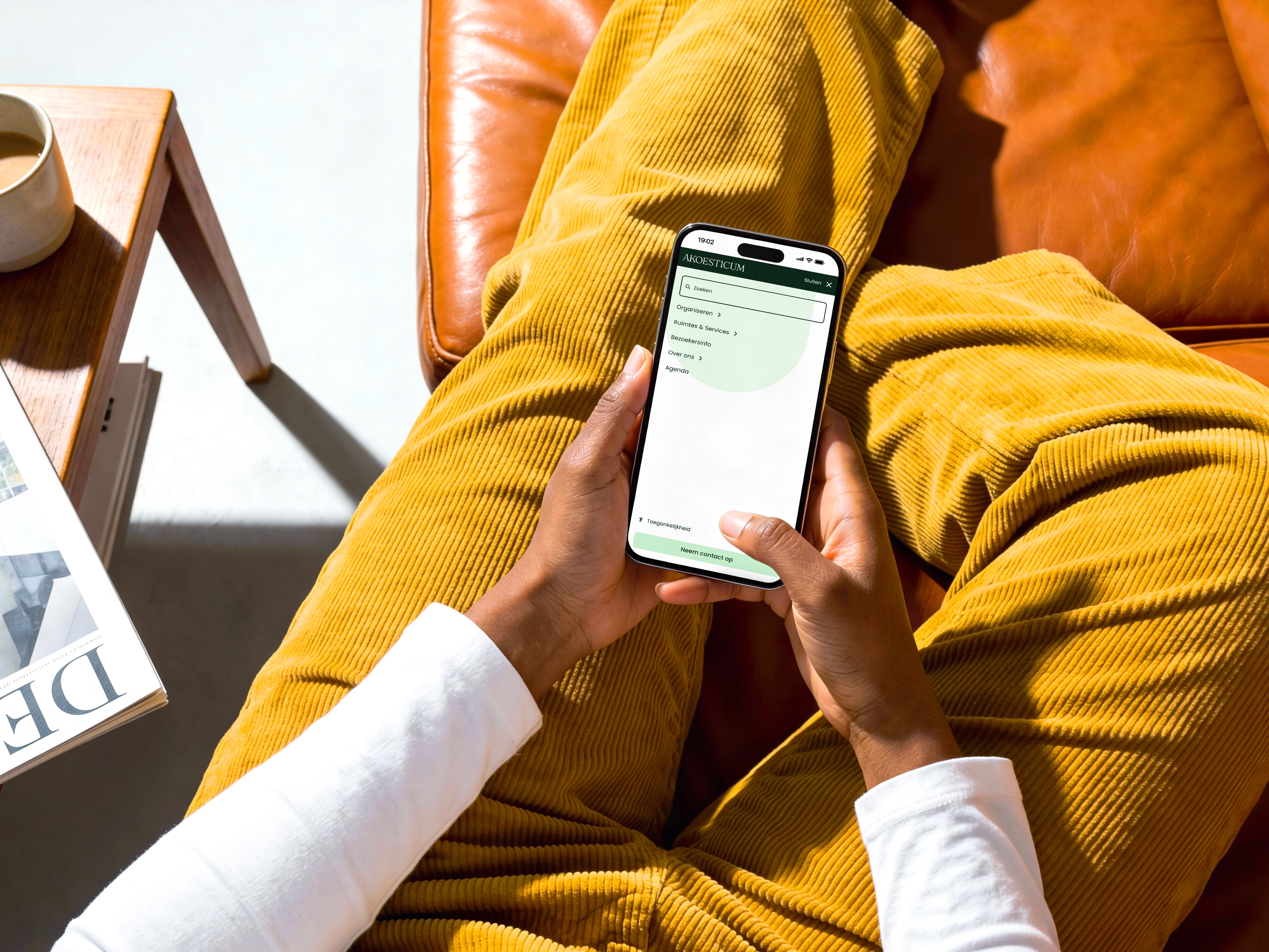 Persoon zit op leren bank met smartphone in hand en navigatie-app zichtbaar op scherm