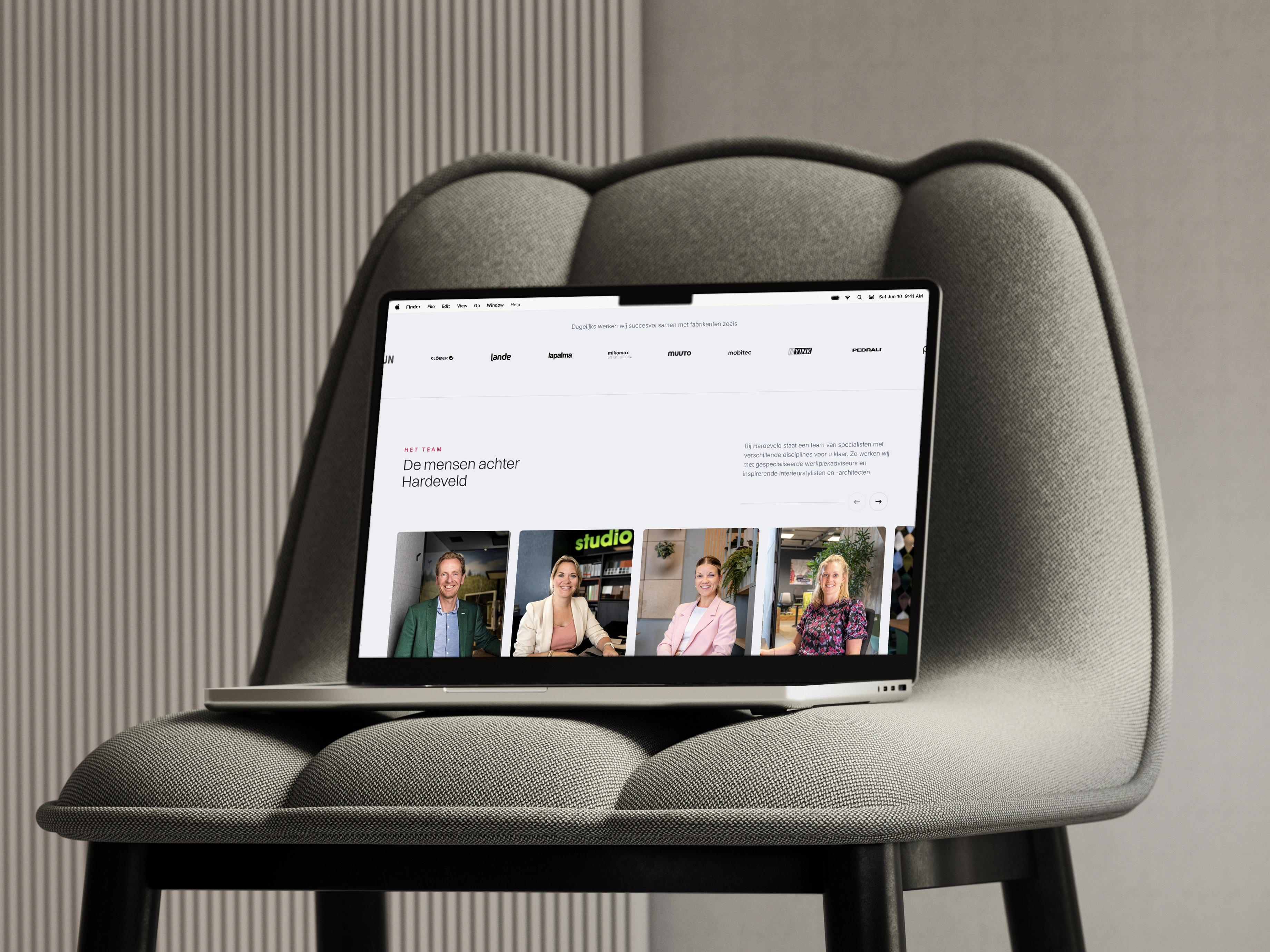 Laptop op een moderne stoel toont website met teamfoto's en beschrijvingen tegen neutrale achtergrond